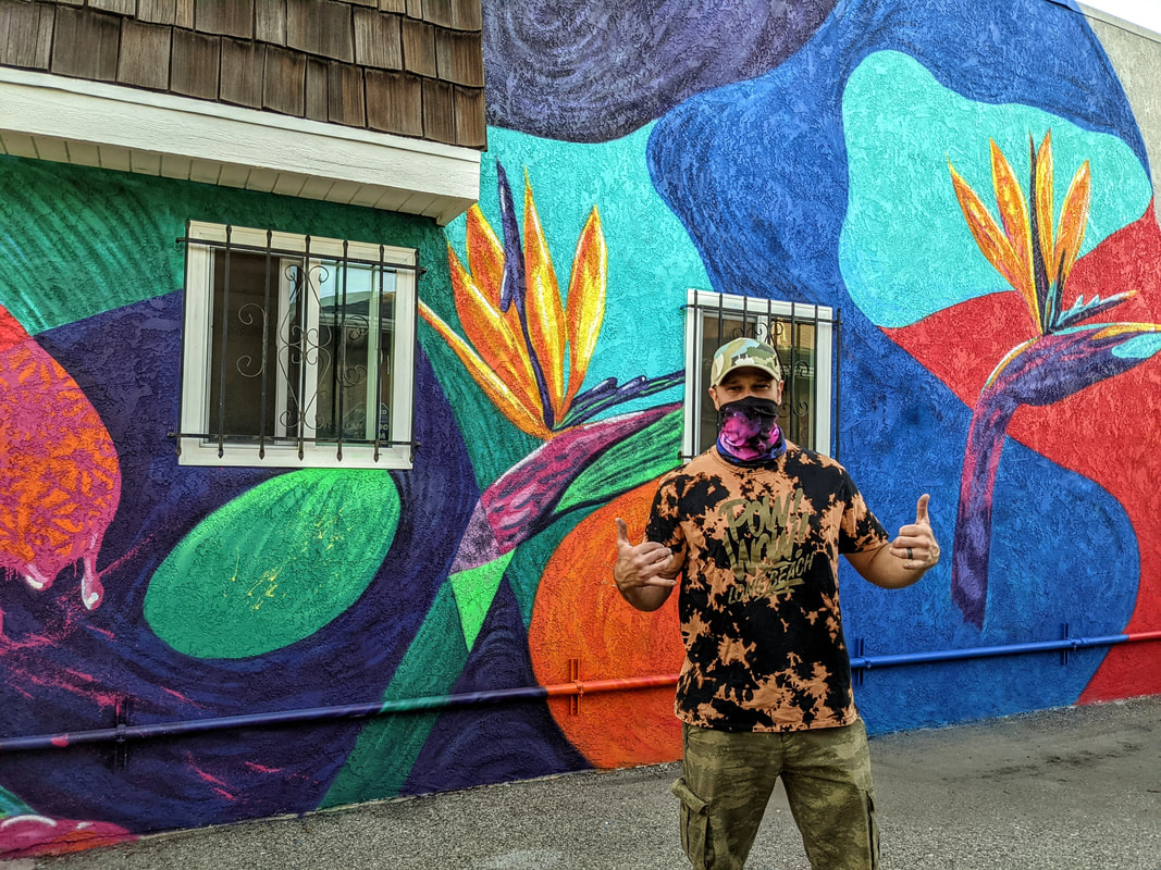 Adam standing in front of completed tropical mural